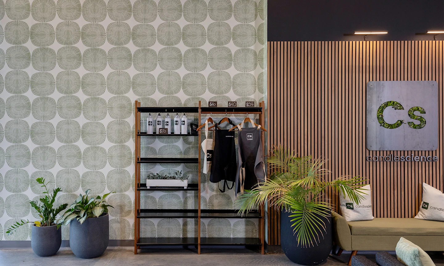 Candle Science office space with a shelf, plants and couch with green geometric wallpaper.