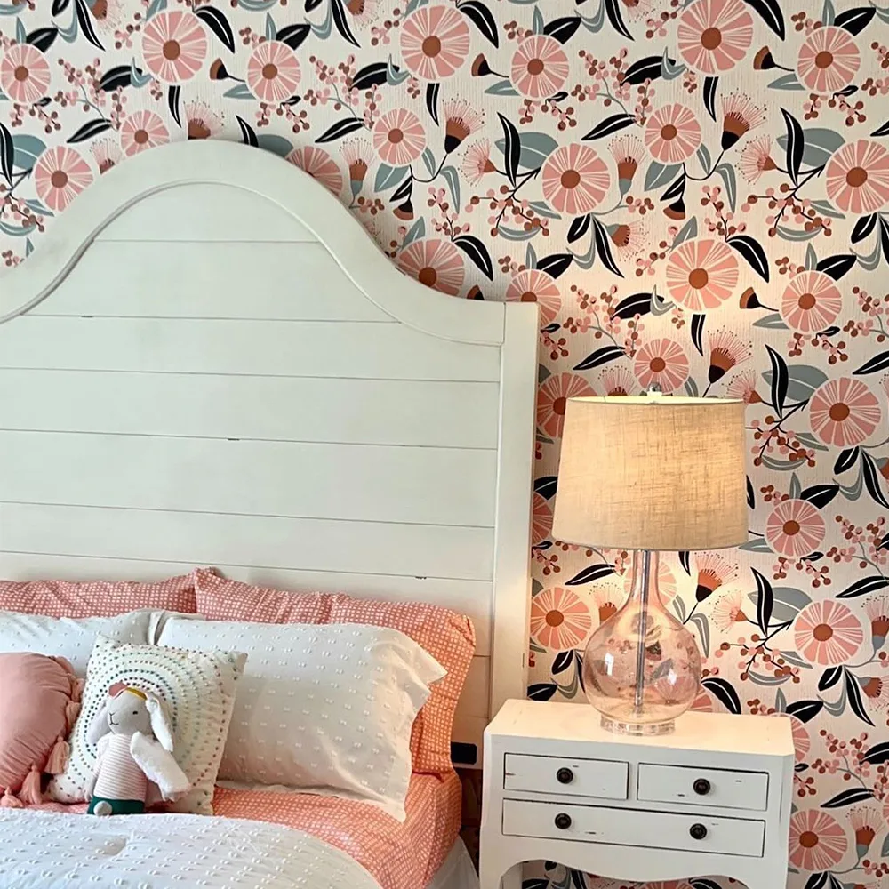 Girls bedroom with pink floral wallpaper behind the bed.