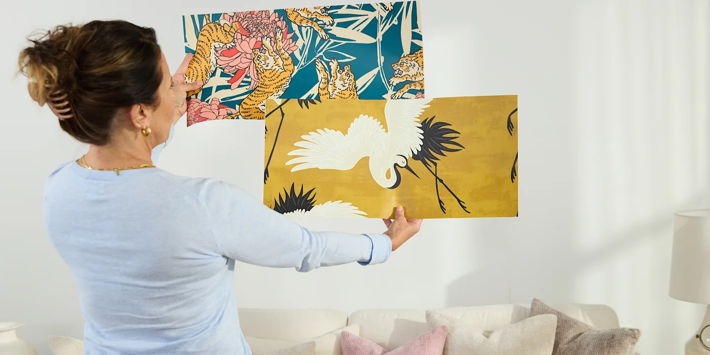 Person assessing two wallpaper samples.