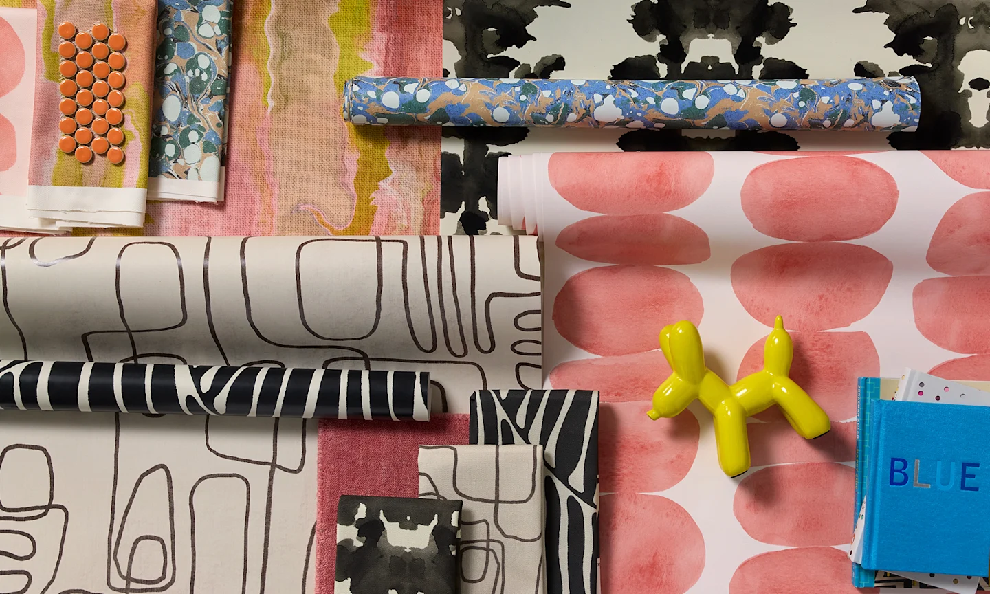 Modern style wallpaper rolls and fabric swatches.