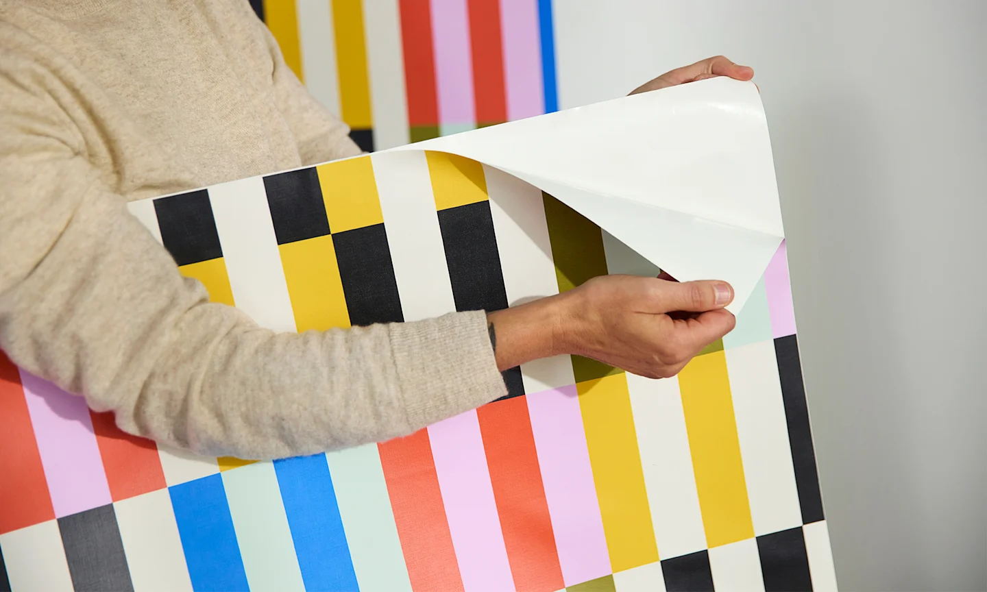 Person installing peel and stick wallpaper on a wall.