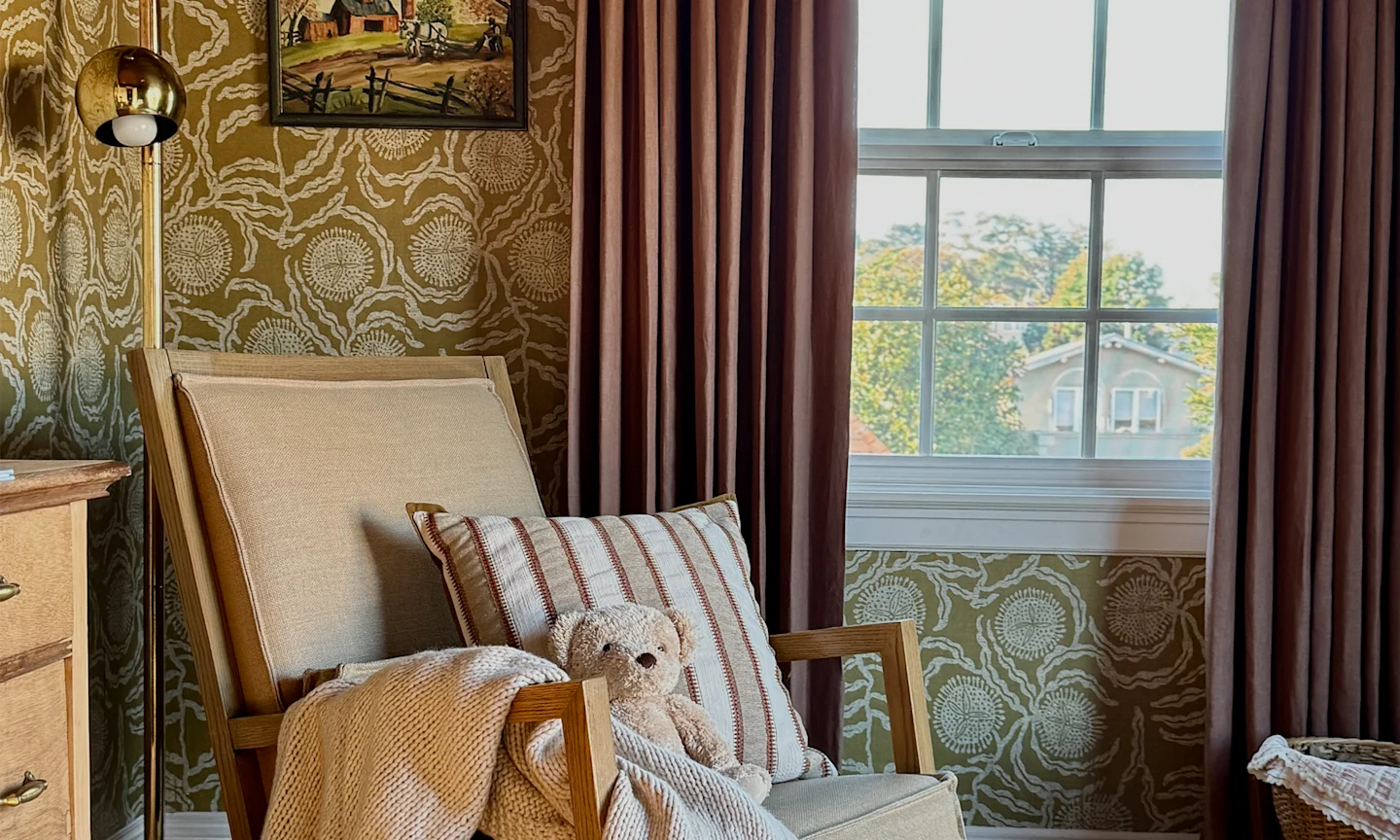 Nursery with tan floral wallpaper and purple curtains.