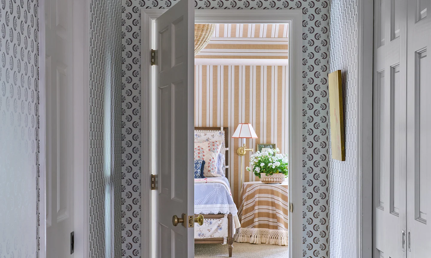 Hallway with wallpaper in Saz Crescent design and a bedroom with a tan stripe wallpaper.