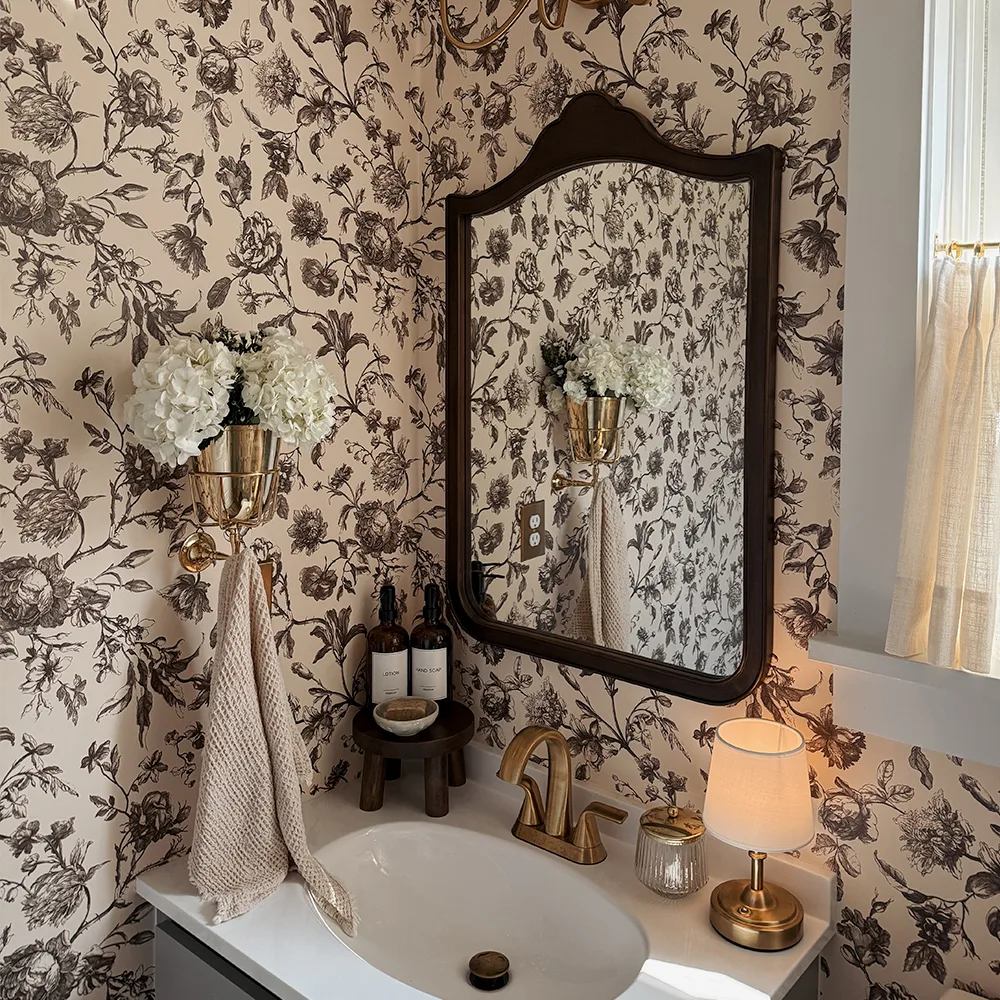 Bathroom with neutral floral toile wallpaper.
