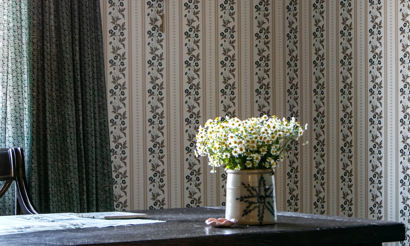 Home office with striped floral wallpaper.