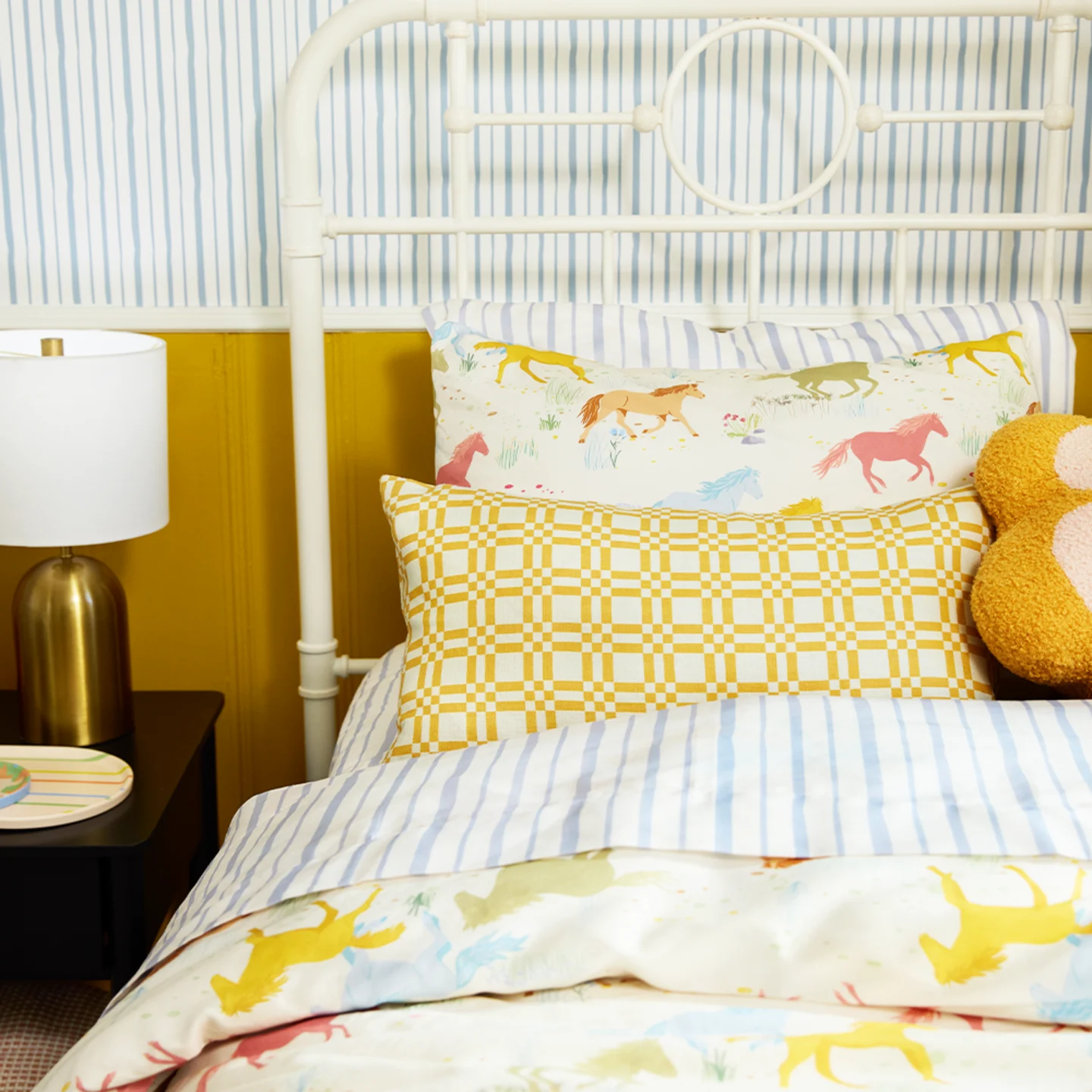 A kids bedroom with striped, check, and whimsical horse bedding.